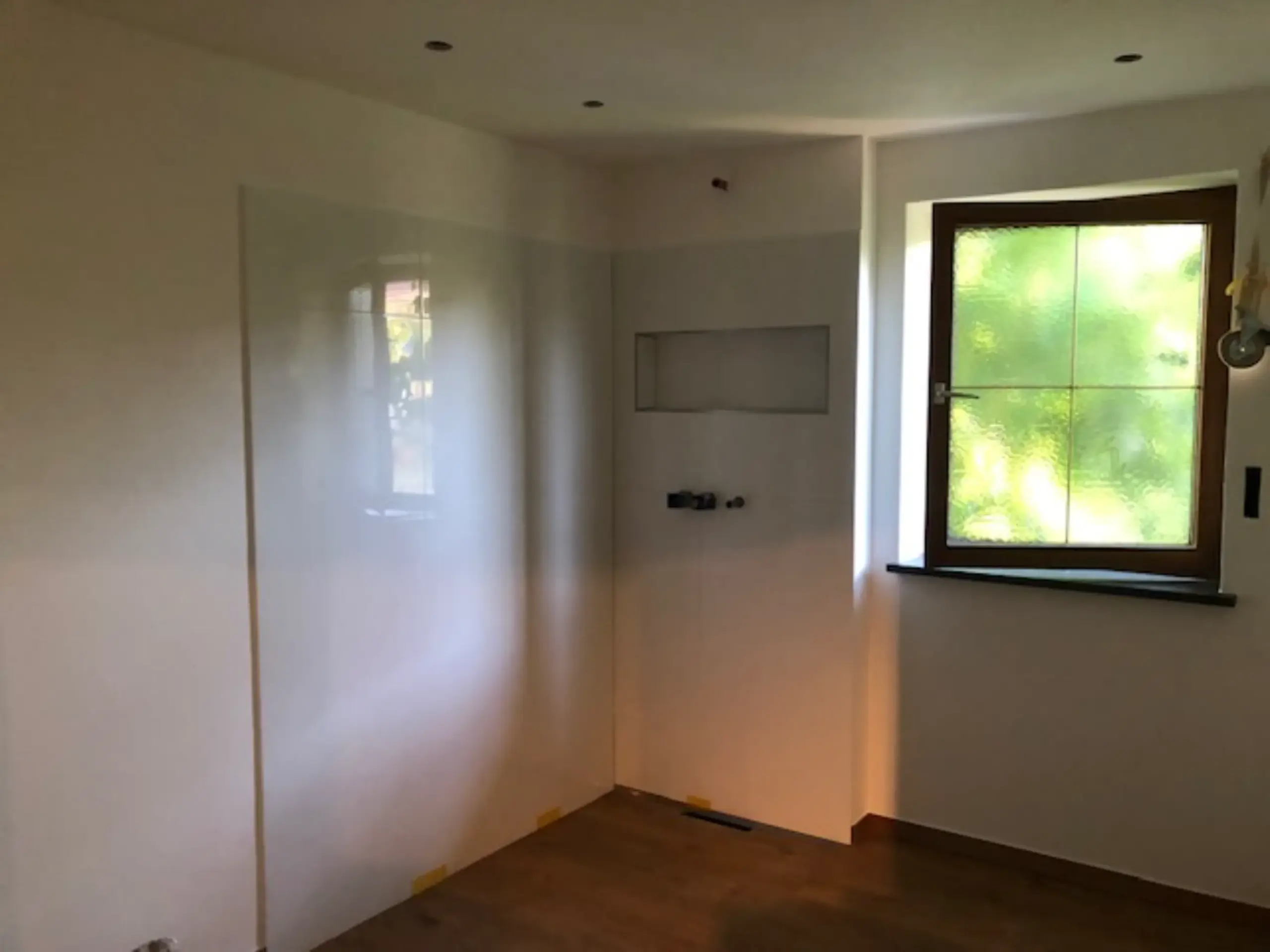 Badezimmer im Rohbau mit verputzten Wänden, vorbereiteten Leitungen und Fenster – Säfke Bau München.